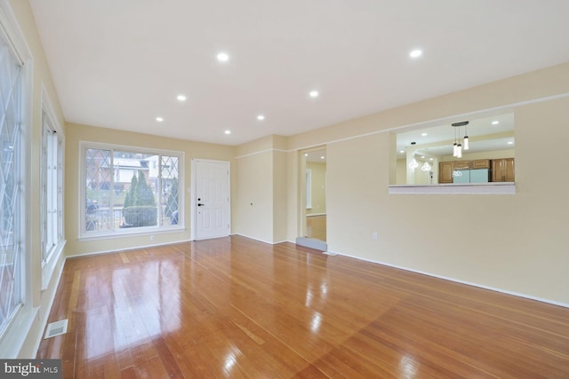 unfurnished living room with wood finished floors, visible vents, and recessed lighting