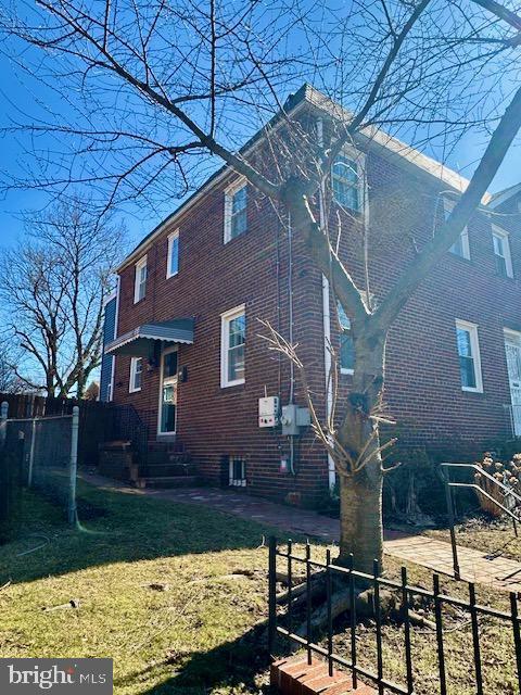 view of property exterior with a yard, brick siding, fence, and central air condition unit