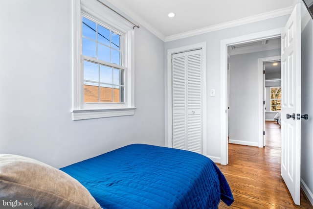 bedroom featuring recessed lighting, wood finished floors, baseboards, ornamental molding, and a closet