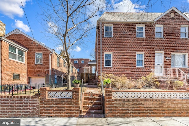 view of front of home featuring brick siding, a fenced front yard, and an attached garage