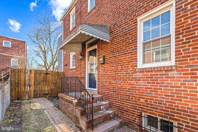 doorway to property with fence and brick siding