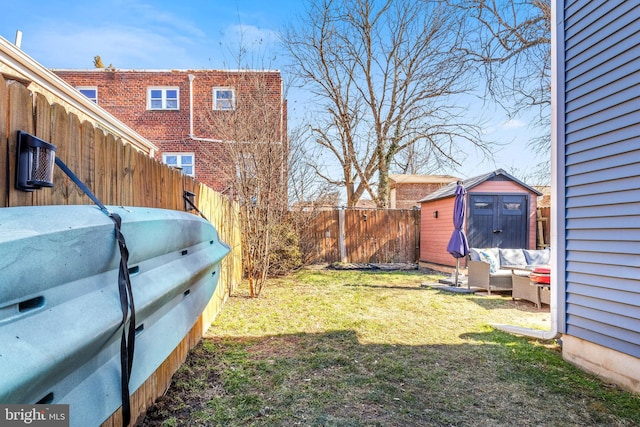 view of yard with a fenced backyard, a storage unit, an outdoor living space, and an outbuilding