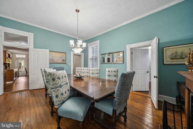 dining area with dark wood-type flooring, crown molding, and a chandelier