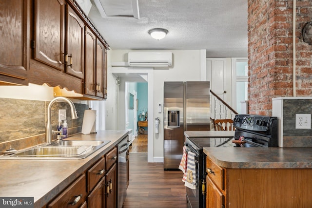 kitchen with a wall mounted air conditioner, stainless steel appliances, sink, a textured ceiling, and dark wood-type flooring