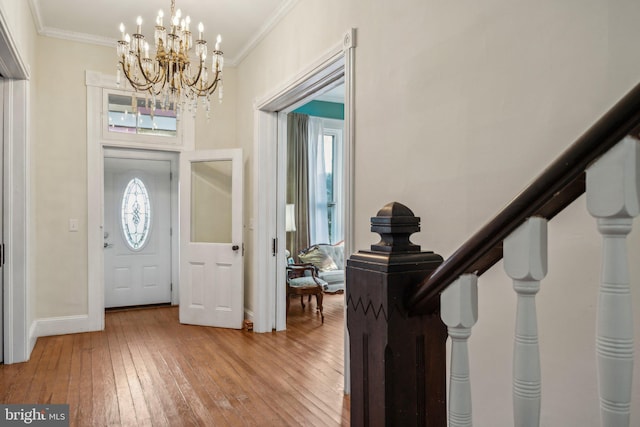 foyer featuring hardwood / wood-style flooring, crown molding, and a notable chandelier