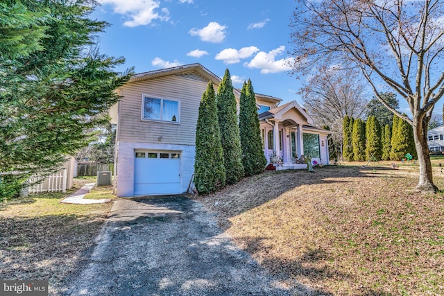 view of front of home featuring driveway, brick siding, an attached garage, and fence