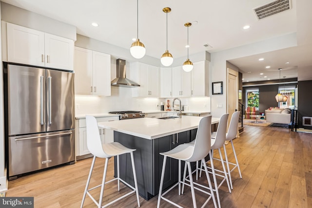 kitchen with white cabinets, sink, high quality fridge, and wall chimney range hood