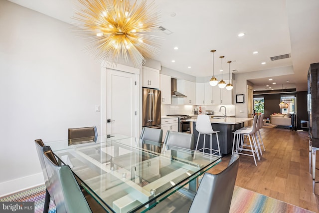 dining area with an inviting chandelier, wood-type flooring, and sink