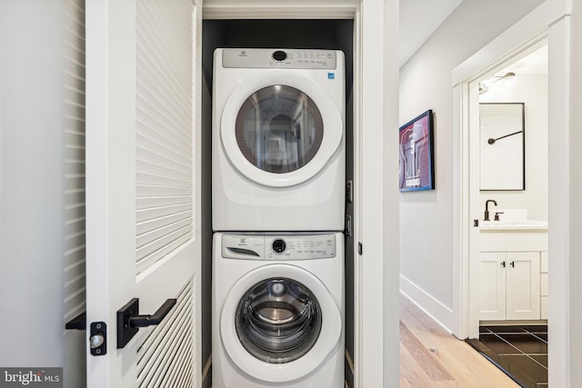 laundry area with sink, stacked washer / drying machine, and hardwood / wood-style floors