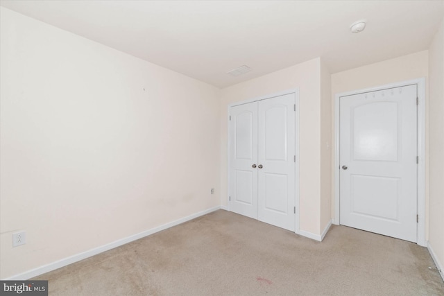 unfurnished bedroom with light carpet and a closet