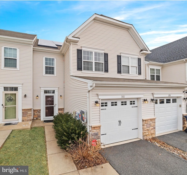 townhome / multi-family property featuring a garage and solar panels