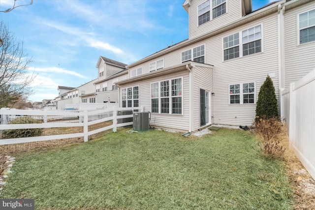 rear view of property with central AC unit and a lawn