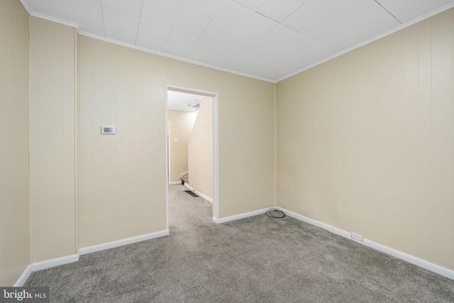 carpeted empty room featuring baseboards and crown molding