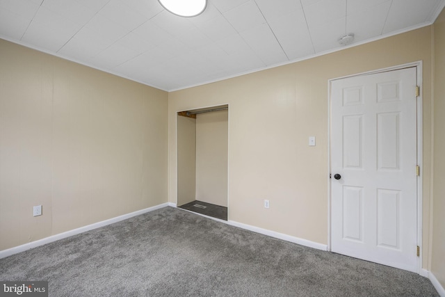 carpeted spare room featuring crown molding and baseboards