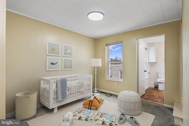 carpeted bedroom featuring a nursery area, crown molding, and baseboards