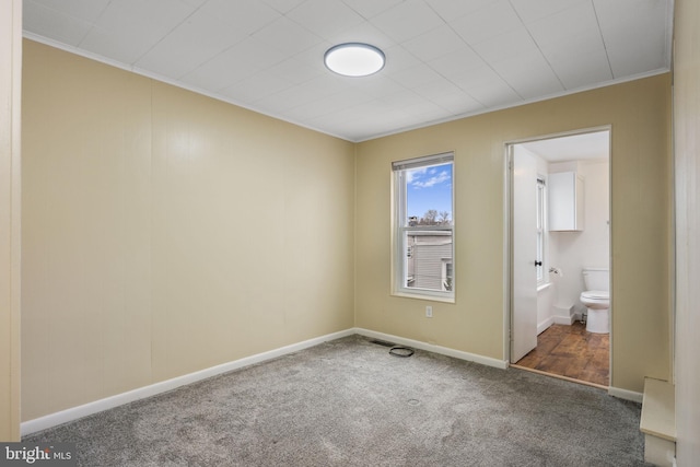 unfurnished bedroom with crown molding, carpet flooring, connected bathroom, and baseboards