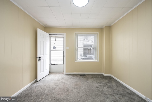 carpeted spare room featuring visible vents, crown molding, and baseboards