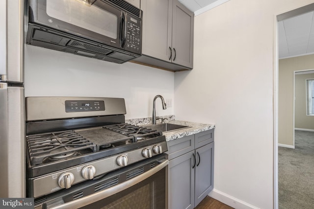 kitchen featuring stainless steel range with gas cooktop, dark carpet, gray cabinetry, ornamental molding, and black microwave