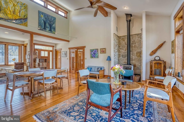 living room with a wood stove, wood finished floors, a wealth of natural light, and ceiling fan