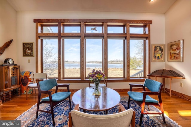 interior space with wood finished floors, a water view, and baseboards