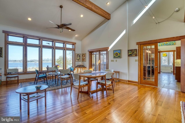 dining space with french doors, beam ceiling, ceiling fan, and light wood finished floors