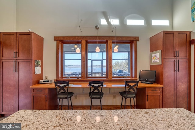 kitchen with light stone counters, brown cabinets, and a towering ceiling