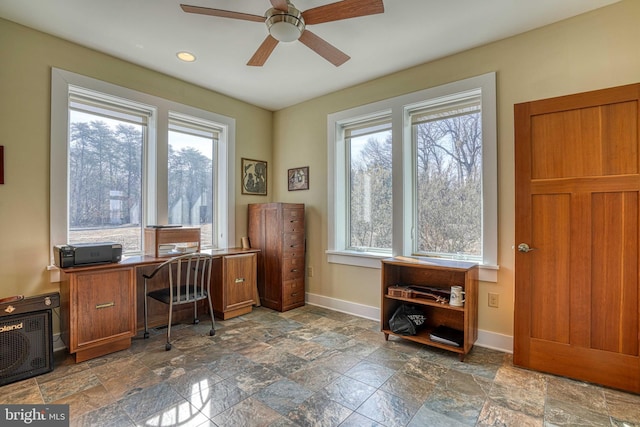 office space with ceiling fan, stone finish flooring, and baseboards