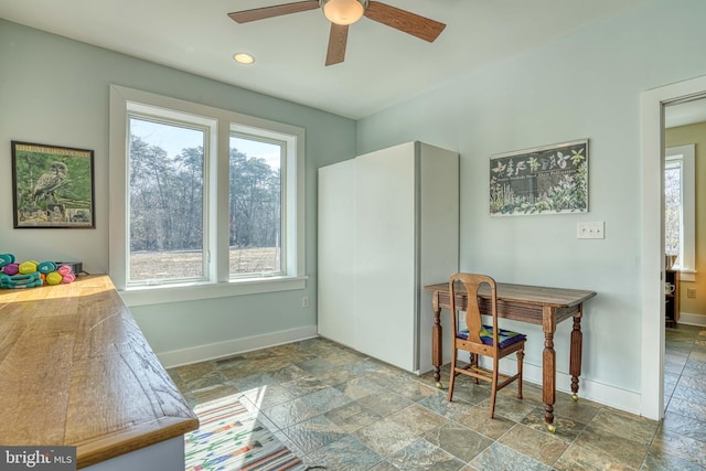 dining area with stone tile floors, baseboards, and ceiling fan