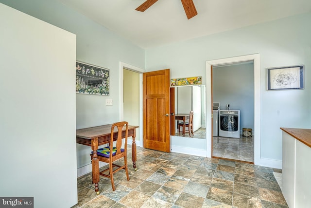 dining room featuring baseboards, a wood stove, ceiling fan, stone finish flooring, and independent washer and dryer