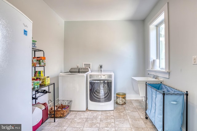 clothes washing area featuring light tile patterned flooring, laundry area, independent washer and dryer, and a sink