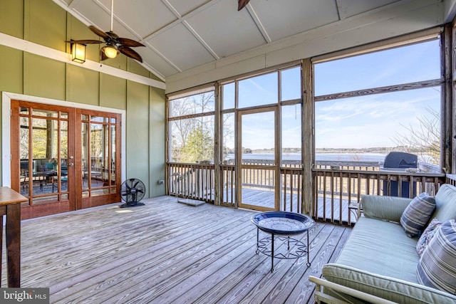 sunroom / solarium featuring french doors, lofted ceiling, ceiling fan, and a water view