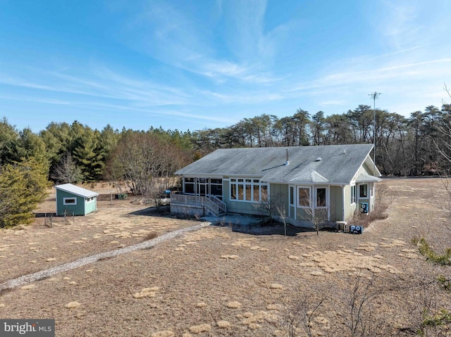 view of front facade featuring dirt driveway and a shingled roof