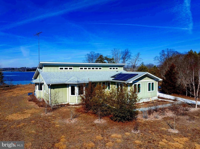 view of front of home featuring solar panels, board and batten siding, and roof with shingles