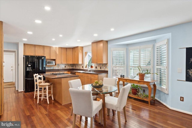 kitchen with dark wood-type flooring, light brown cabinets, backsplash, a center island, and stainless steel appliances