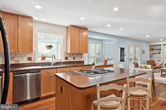 kitchen with a sink, light wood-type flooring, a kitchen bar, and stainless steel appliances