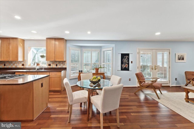 kitchen with cooktop, dark wood-style floors, decorative backsplash, and a sink