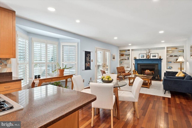 interior space featuring built in shelves, dark wood-style floors, recessed lighting, and a lit fireplace