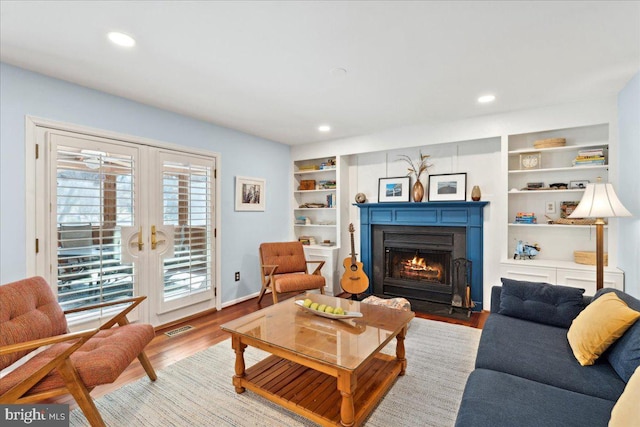 living area with visible vents, a fireplace with flush hearth, recessed lighting, french doors, and wood finished floors