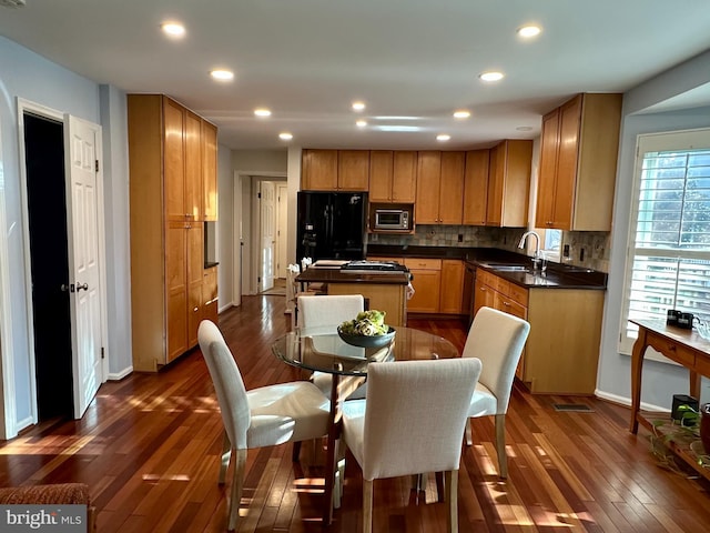 kitchen featuring dark countertops, stainless steel microwave, a center island, freestanding refrigerator, and dark wood-style floors