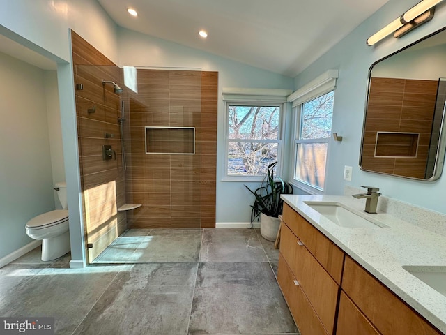 full bathroom with baseboards, a tile shower, a sink, vaulted ceiling, and toilet