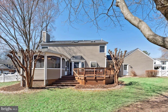 back of property featuring fence, a wooden deck, a yard, a sunroom, and a chimney