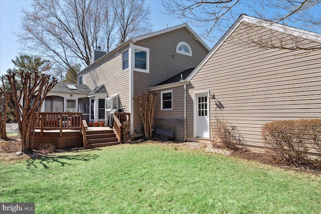 back of property with a yard, a deck, and a chimney