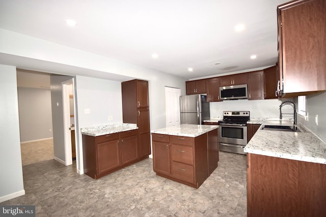 kitchen with light stone counters, a center island, stainless steel appliances, and a sink