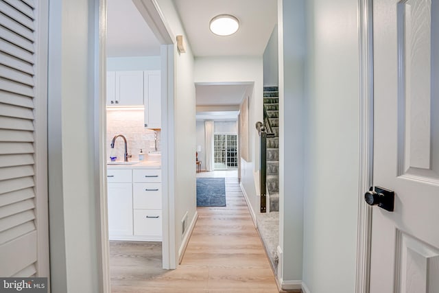 hallway with light wood finished floors and a sink