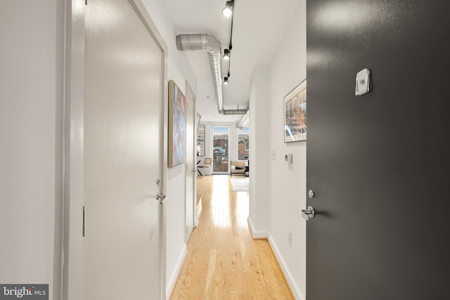 corridor featuring light wood-style flooring and baseboards