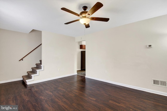 empty room featuring dark wood-style floors, baseboards, stairs, and visible vents