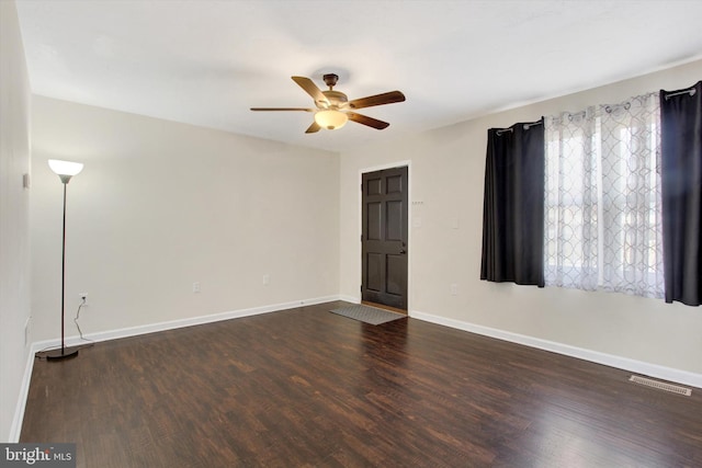 interior space with a ceiling fan, baseboards, visible vents, and dark wood-style flooring