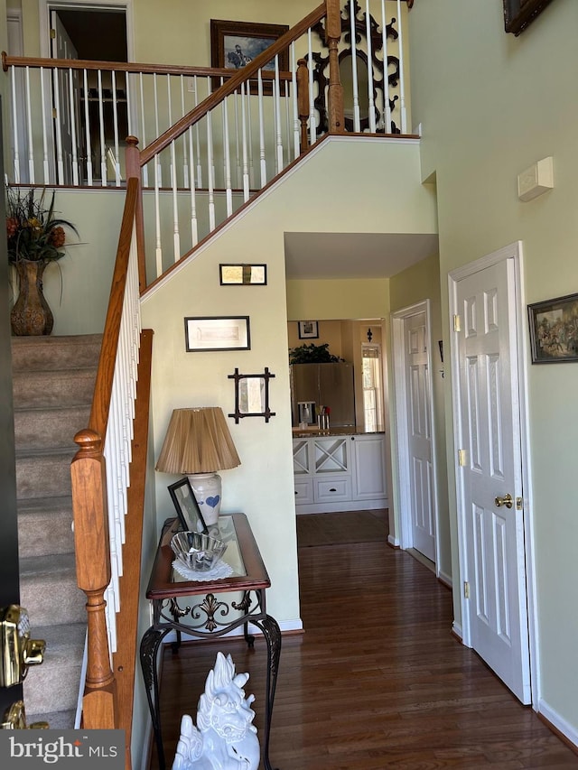 stairway with hardwood / wood-style flooring and a high ceiling