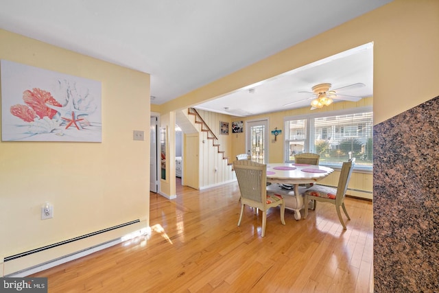 dining space with ceiling fan, light hardwood / wood-style flooring, and a baseboard heating unit