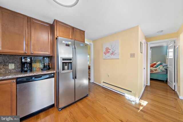 kitchen with light hardwood / wood-style floors, appliances with stainless steel finishes, backsplash, and a baseboard radiator